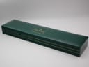The closed original green Gucci branded box, displaying the gold Gucci logo on top.