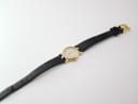 Overhead view of the Gucci 3400 L watch laid flat, displaying the full length of the black leather strap and gold-tone case.