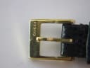 Close-up of the gold-tone buckle, clearly engraved with the 'GUCCI' brand name.