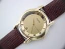 Close-up of the Gucci 5100 M watch dial, showcasing the gold finish, Roman numerals, date window, and 'SWISS MADE' text.