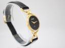 Angled view from the left side of the Gucci 6000L watch on a display stand, showcasing the integrated gold-tone links.