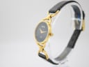 Angled side view of the Gucci 6000L watch on a display stand, highlighting the gold-tone case and crown.