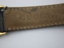 Close-up of the underside of the black leather strap, showing faint 'GUCCI' embossing and signs of wear.