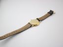 Back view of the Gucci 3000 M watch lying flat, revealing the underside of the strap and the gold-plated case back.
