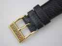 Close-up of the gold-tone buckle, clearly signed "GUCCI" in an engraved font.