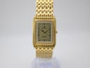 Front view of Sandoz rectangular gold-tone watch with champagne dial and rhinestone bezel on a clear stand.
