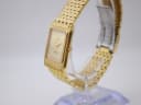 Right-side view of the Sandoz watch on a stand, showing the crown and gold-tone bracelet.