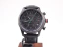 Front view of the black Gucci 126.2 chronograph watch with green accents, on a watch stand.