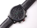 Top-down view of the black Gucci 126.2 chronograph watch and its patterned leather strap.