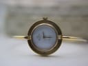 Front view of the Gucci change bezel watch with a plain gold coloured bezel, showing the white dial with Gucci Italy logo.