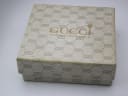 Close-up of the original beige Gucci watch box, patterned with the interlocking GG logo and "GUCCI 27 OLD BOND STREET LONDON W1" text.