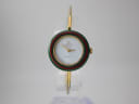 Front view of the Gucci change bezel watch with a green and red striped bezel, displayed on a clear watch stand.