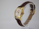 Angled view of the Tissot watch on a display stand, highlighting the textured fluted bezel and gold tone crown.