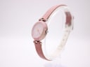 Side profile of the Tissot RockWatch on a clear stand, showing the round pink stone case and crown.