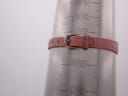 Side view of Tissot RockWatch pink leather strap on a wrist sizing cone, showing a Tissot-signed buckle and approximate wrist circumference markings.