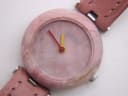 Close-up of the Tissot RockWatch pink stone dial, showing Tissot logo, hands, and "Swiss Made" text.