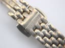 Close-up of the signed Tissot butterfly clasp on the gold tone steel bracelet.