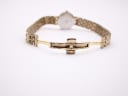 Rear view of the Tissot watch with the gold tone butterfly clasp open, showing the internal mechanism of the clasp.
