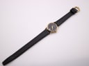 Top-down view of the Raymond Weil watch and full black leather strap with gold tone buckle