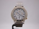Front view of the Accurist Commemoratives GM1009 watch on a stand, showcasing the white dial with Roman numerals and gold-tone compass bezel.