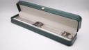 The GUCCI 7700L watch with its mesh bracelet lying inside a generic green presentation box.