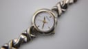 Close-up of the Bulova watch dial, showing the white vertically textured face, gold baton indices, and 'BULOVA' branding.