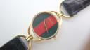Close-up of the Gucci dial with red and green stripe, gold hands, and gold-tone case with signature lugs.