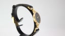 Profile view of the Gucci 6000L watch on a stand, highlighting the slender case design and how the strap integrates with the gold-toned links.