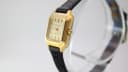 Side profile of the Bulova watch, highlighting the gold tone case, fluted crown, and black leather strap.
