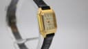 Angled view of the Bulova watch, showing the gold tone case and the textured black leather strap.