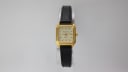 Front view of the Bulova quartz watch, showing its gold tone octagonal case and cream dial with black leather strap.