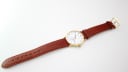 Full length view of the Mappin & Webb watch with its brown leather strap and gold-tone buckle, laid flat.