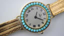 Detailed close-up of the Yema watch dial, highlighting the gold-tone case, turquoise bezel, silver dial, and black roman numeral markers.