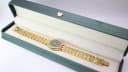 Overhead view of the gold tone Tissot Stylist watch in a green presentation box.