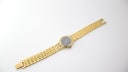 Full length view of the gold tone Tissot Stylist watch with the bracelet laid out and clasp open.