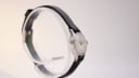 Opposite side profile view of the Bucherer watch on a display stand, showing the curved lugs and case shape.
