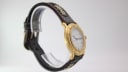Oblique side view of the Michel Jordi watch on a display stand, highlighting the decorated leather strap and buckle.