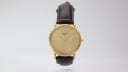 Front view of the Tissot T870/970 watch with a gold dial and brown leather strap on a light background.