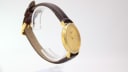 Another angled side view of the Tissot watch, highlighting the slim profile of the gold-tone case.