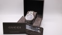 The Gucci 8900 M watch presented in its original dark brown manufacturer's box with accompanying papers and a warranty booklet.