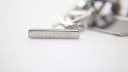 Close-up of the rectangular stainless steel charm attached to the bracelet, clearly engraved with the 'GUCCI' name.