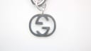 Close-up of the iconic interlocking 'G' logo charm, crafted from stainless steel, dangling from the watch bracelet.