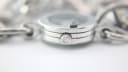 Extreme close-up of the Gucci branded crown, detailed with the interlocking G logo, and the stacked construction of the watch case.