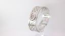 Angled side view of the Gucci T.1.2 watch, highlighting the engraved 'GG' monogram on the bangle.