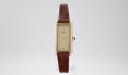 Front view of Raymond Weil 310 ladies' manual wind watch, showing gold-tone rectangular case, champagne dial with diamond, and brown leather strap.