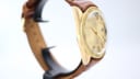Left side profile view of the gold-tone Royce watch case, showcasing its vintage lines and brown leather strap.