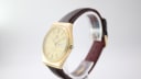 Angled side view of the Tissot Seastar Quartz watch, highlighting the brushed finish of its gold octagonal case and the texture of the brown leather strap.