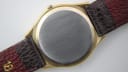 View of the polished stainless steel case back of the Tissot Seastar Quartz, framed by the gold octagonal case and the attached brown leather strap.