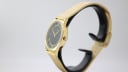 Angled side view of the gold Limit watch case and crown on a black stand.