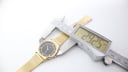 Digital caliper measuring the watch case diameter at 29.25mm, showing the gold mesh bracelet.